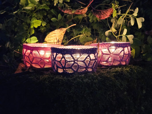 Three glass ramekins with crochet covers and a tealight inside.