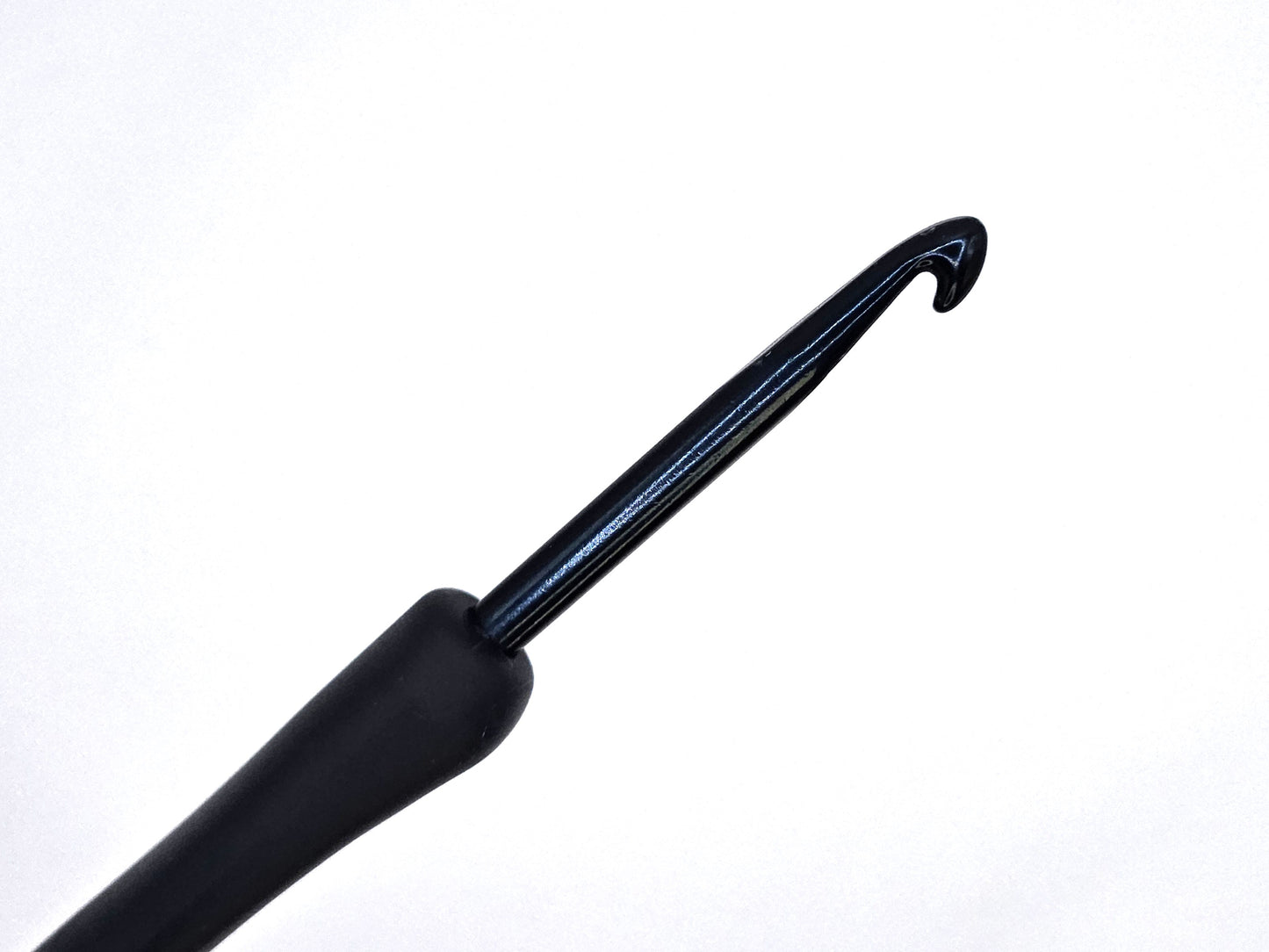 Close-up of a soft grip ergonomic crochet hook with a black rubberised handle and smooth metal tip, displayed against a white background.