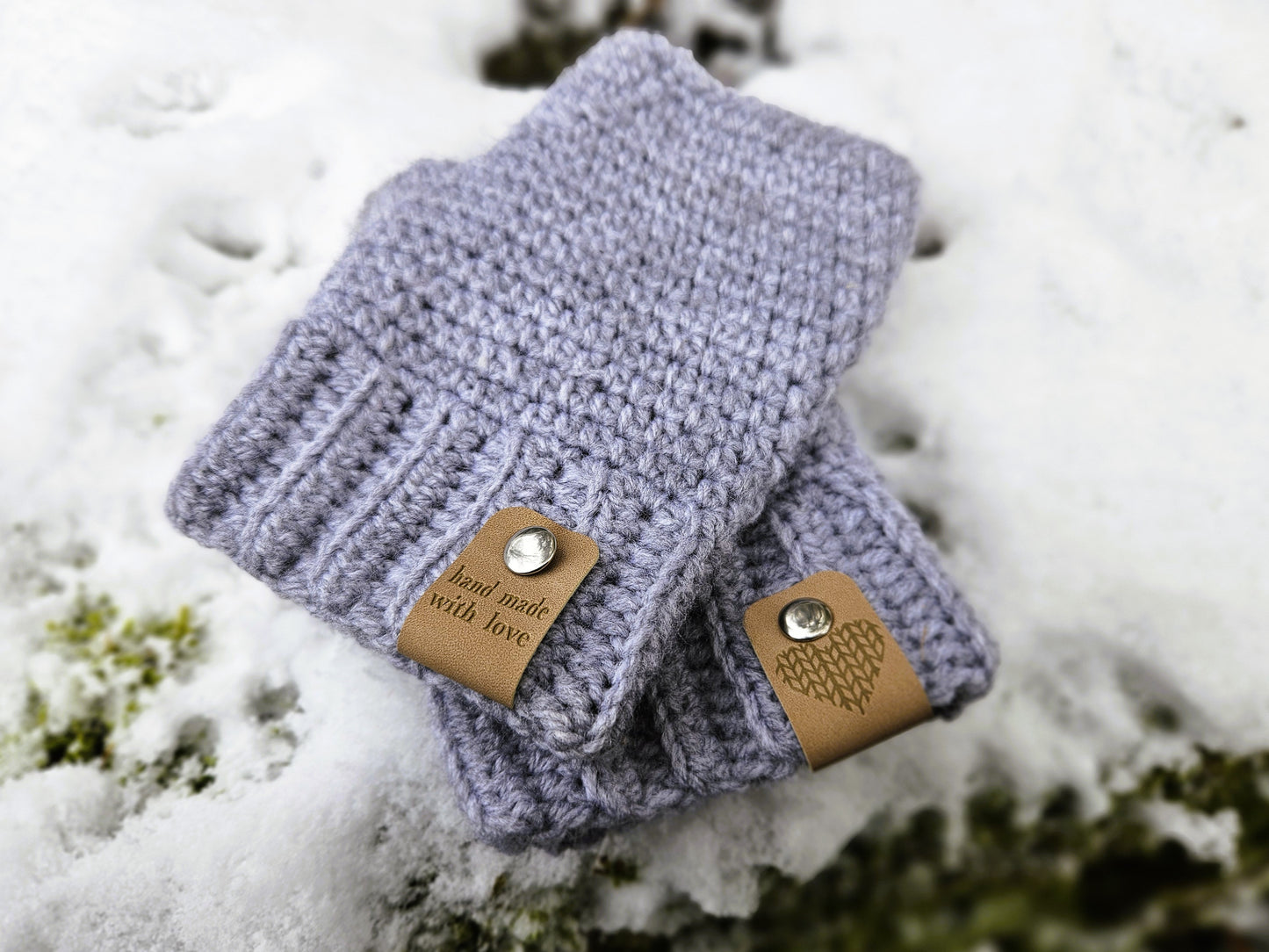 Two beige faux leather hand made with love tags displayed on a pair of crochet gloves, secured with metal poppers. One tag has the writing hand made with love facing. the other tag has a heart design.