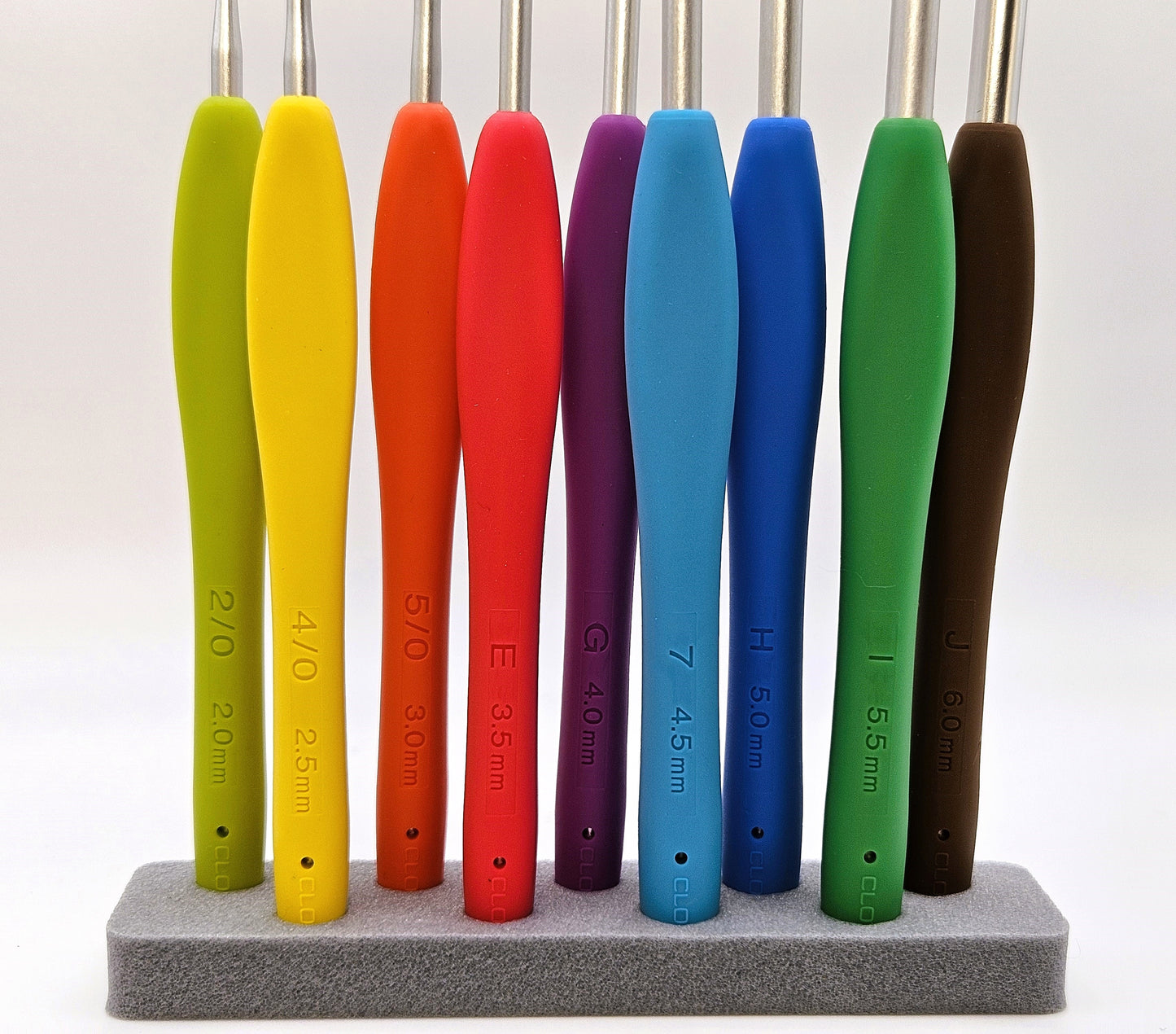 Set of Clover Amour Crochet Hooks in vibrant colours, displayed upright in a foam holder with size markings visible on each handle.